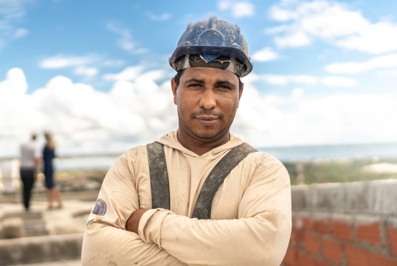 Construction worker wearing a hard hat standing outdoors with arms crossed.