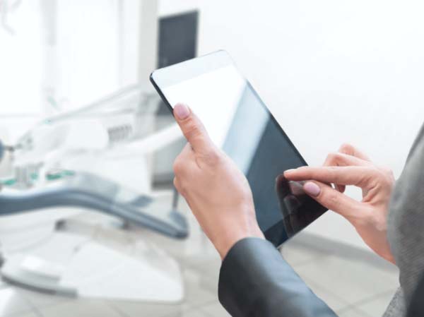 Person using a digital tablet in a dental office setting.